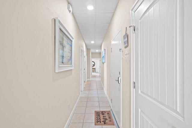 hallway with light tile patterned floors and a paneled ceiling