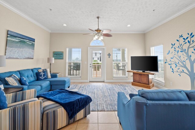 living room with a textured ceiling, ornamental molding, light tile patterned flooring, and ceiling fan