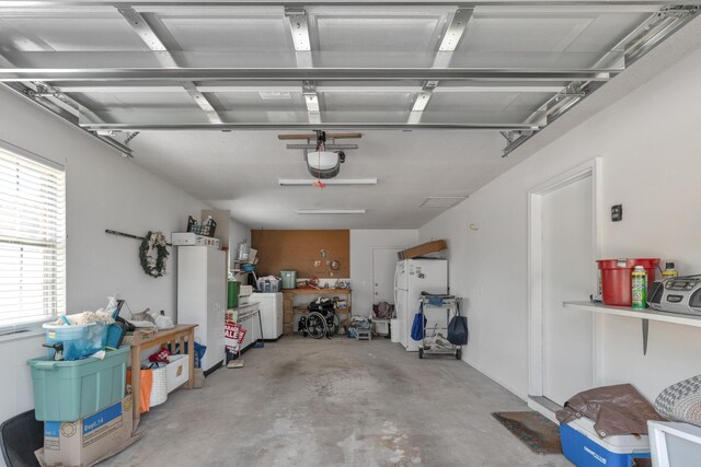 garage with washer / clothes dryer, white refrigerator, and a garage door opener