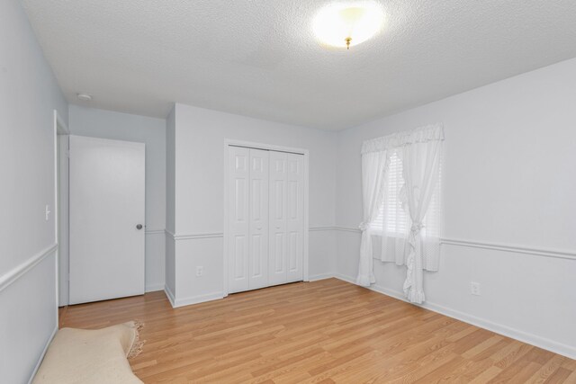 spare room featuring a textured ceiling and light wood-type flooring