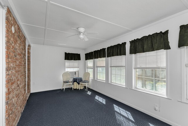 interior space with brick wall, carpet floors, ceiling fan, and a wealth of natural light