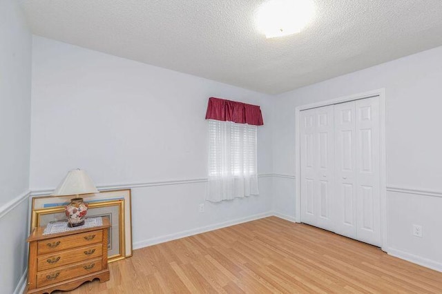 spare room with a textured ceiling and light hardwood / wood-style flooring