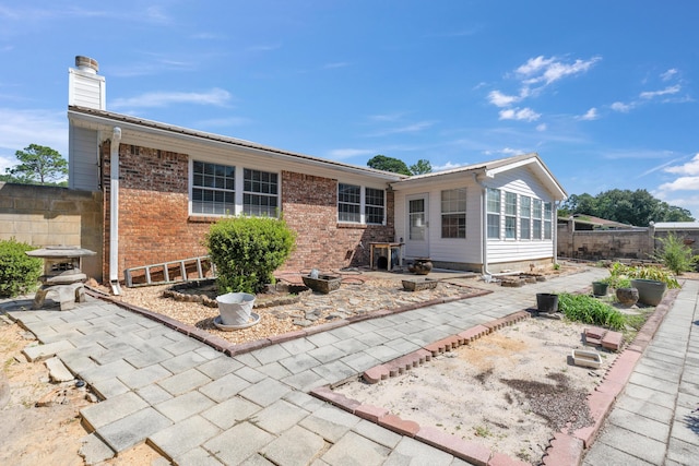 back of property with a sunroom and a patio area