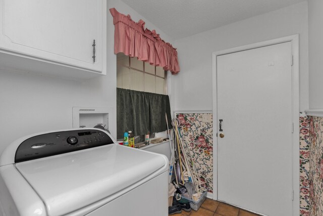 clothes washing area with cabinets, washer / dryer, a textured ceiling, and tile patterned flooring