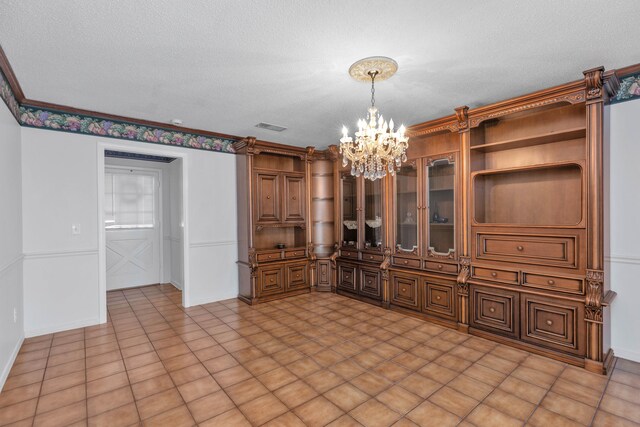 interior space featuring a textured ceiling, ornamental molding, an inviting chandelier, and light tile patterned floors