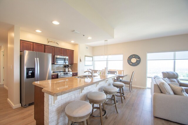 kitchen featuring stainless steel appliances, light wood-type flooring, sink, and a wealth of natural light