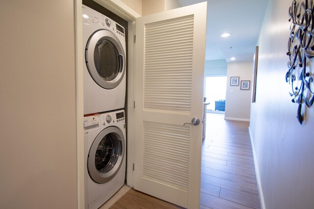 laundry area with hardwood / wood-style flooring and stacked washing maching and dryer