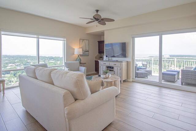 living room featuring ceiling fan, a fireplace, and light hardwood / wood-style floors