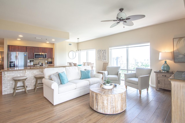 living room with light hardwood / wood-style floors, ceiling fan, and sink