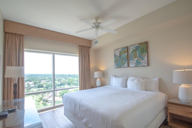 bedroom featuring ceiling fan, light hardwood / wood-style floors, and multiple windows