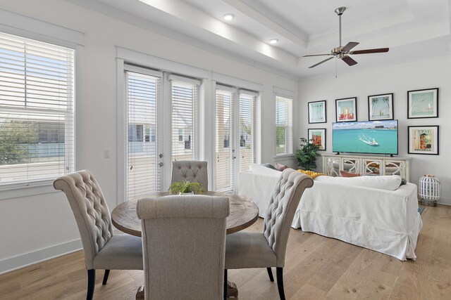 dining area featuring light hardwood / wood-style flooring, ceiling fan, and a raised ceiling