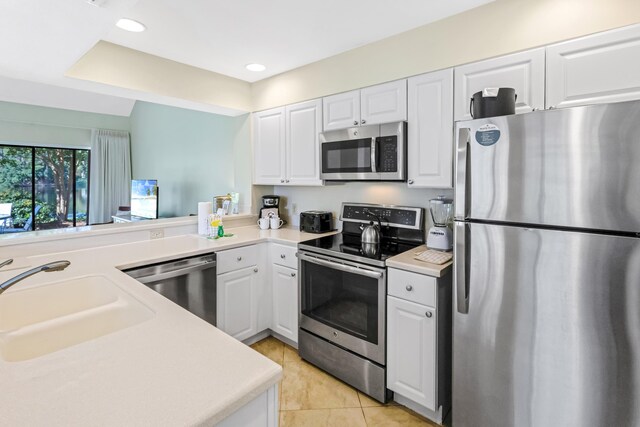 kitchen with sink, light tile patterned floors, white cabinetry, kitchen peninsula, and stainless steel appliances