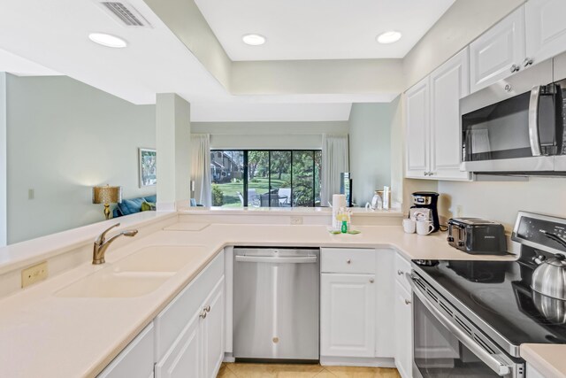 kitchen featuring sink, white cabinets, light tile patterned flooring, and appliances with stainless steel finishes