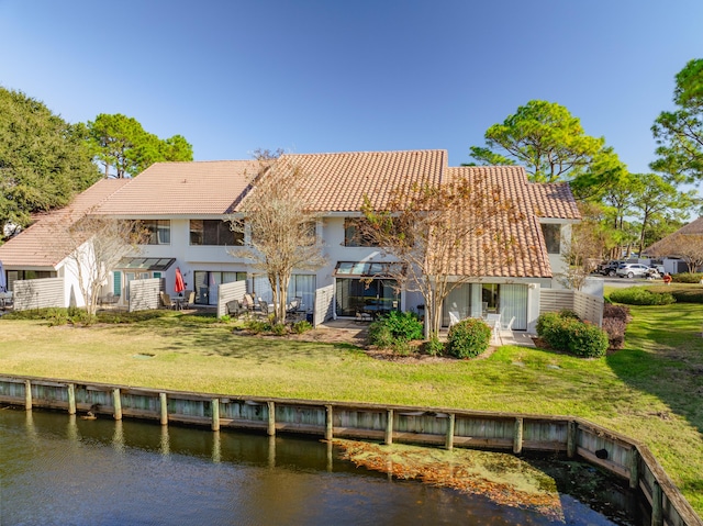 rear view of property with a water view and a lawn