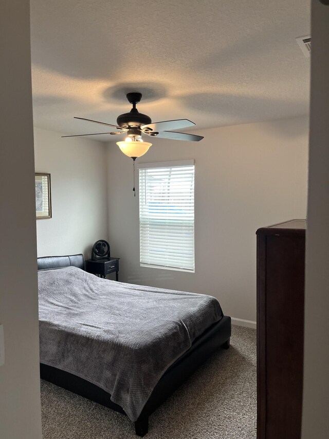 bedroom with ceiling fan, carpet flooring, and a textured ceiling