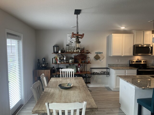 dining space featuring a textured ceiling and light wood-type flooring