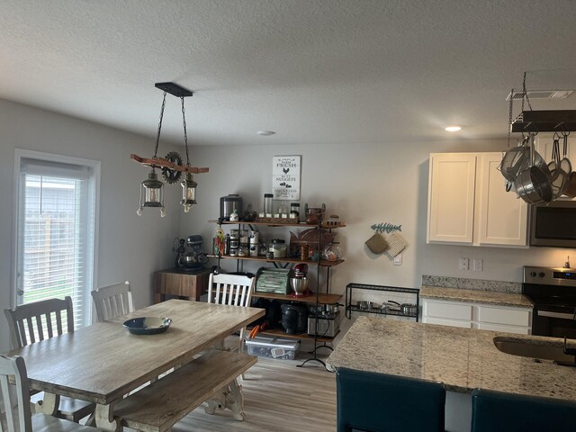 dining space featuring light wood-type flooring and a textured ceiling