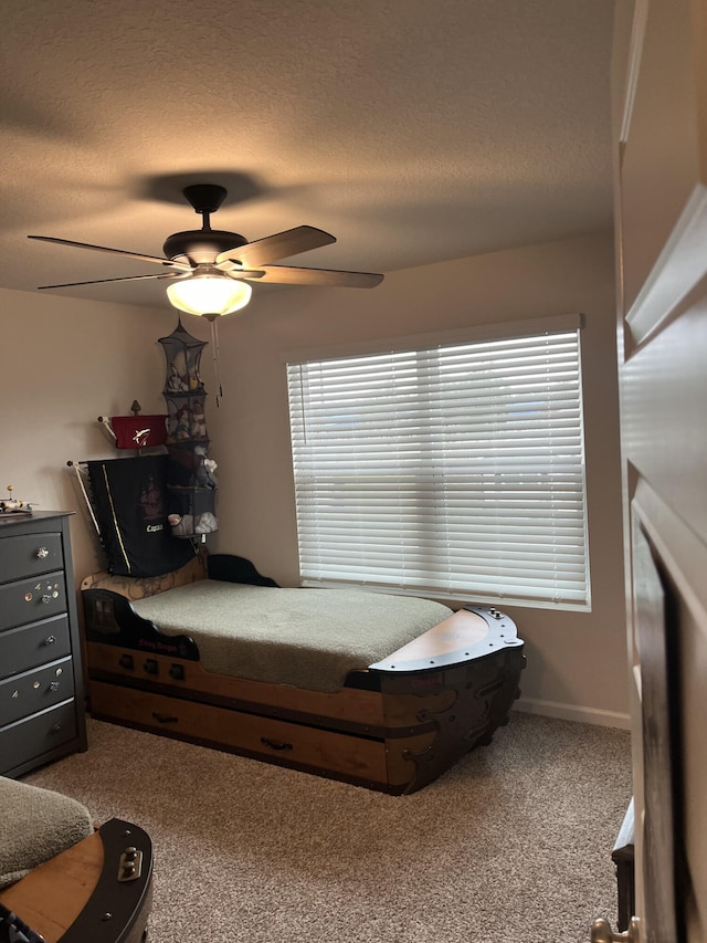 bedroom with ceiling fan, carpet floors, and a textured ceiling