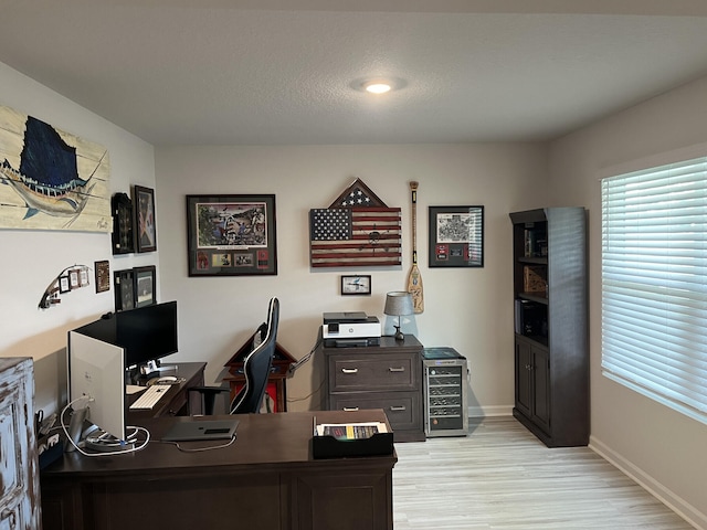 home office featuring light hardwood / wood-style floors and a textured ceiling