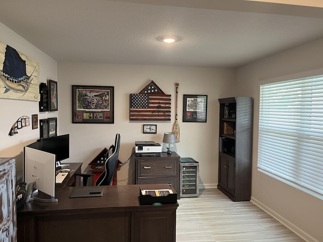 home office with a textured ceiling and light hardwood / wood-style floors