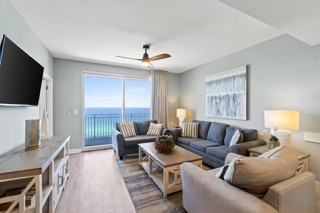 living room with wood-type flooring, a water view, and ceiling fan