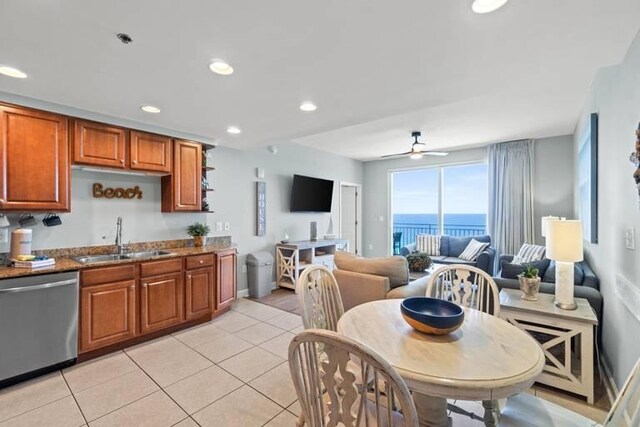 kitchen with light stone counters, light tile patterned floors, ceiling fan, stainless steel dishwasher, and sink