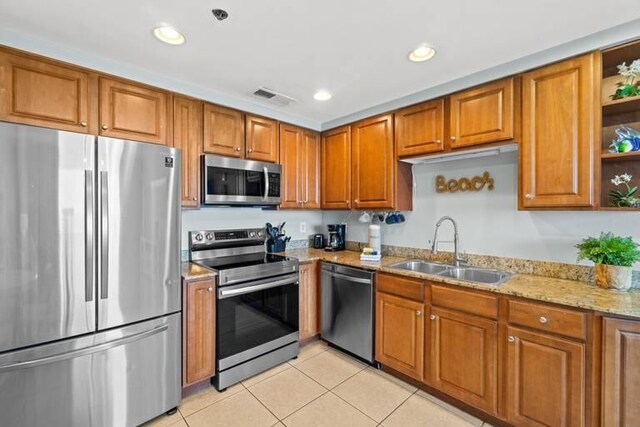 kitchen with sink, light tile patterned floors, stainless steel appliances, and light stone counters