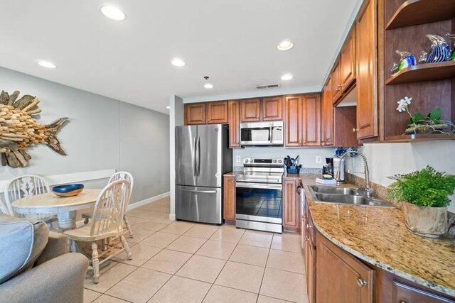 kitchen with light stone counters, light tile patterned floors, stainless steel appliances, and sink