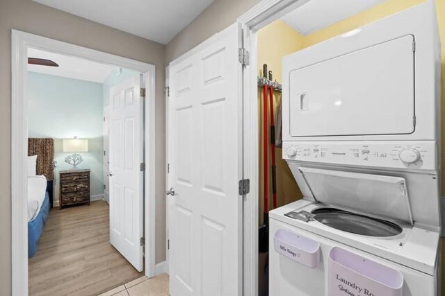 laundry area with light wood-type flooring and stacked washer / dryer