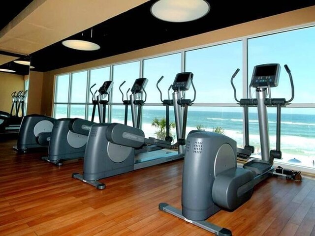 workout area with hardwood / wood-style floors and a water view