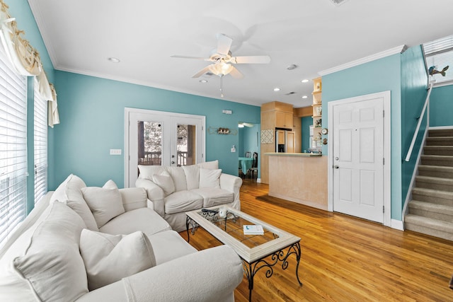 living room with a wealth of natural light, light hardwood / wood-style floors, ceiling fan, and crown molding