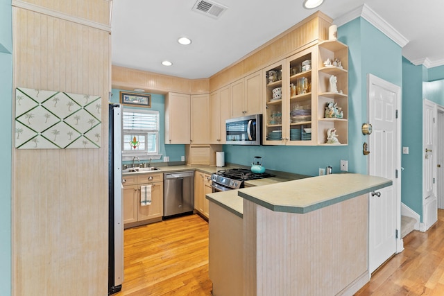 kitchen with appliances with stainless steel finishes, light brown cabinetry, kitchen peninsula, and light hardwood / wood-style floors