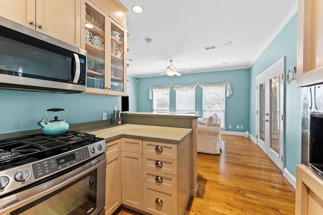 kitchen featuring light hardwood / wood-style floors, kitchen peninsula, stainless steel appliances, crown molding, and ceiling fan