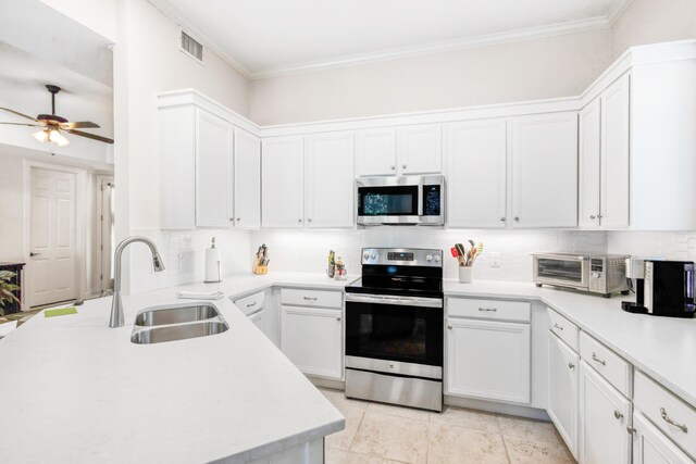 kitchen featuring stainless steel appliances, white cabinetry, sink, ceiling fan, and crown molding