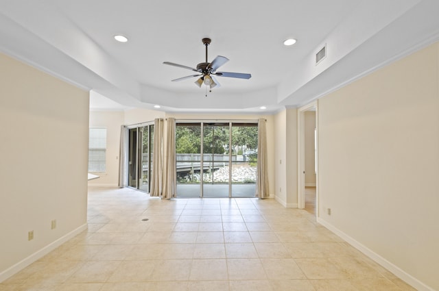 unfurnished room featuring ceiling fan, light tile patterned floors, and a tray ceiling