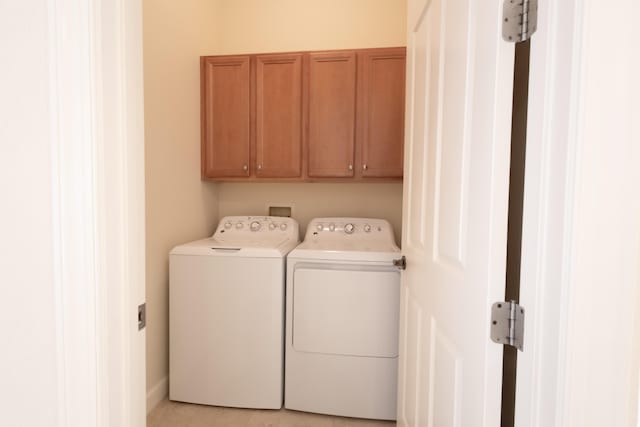 clothes washing area with cabinets and separate washer and dryer