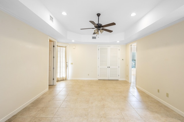 tiled empty room with a tray ceiling and ceiling fan