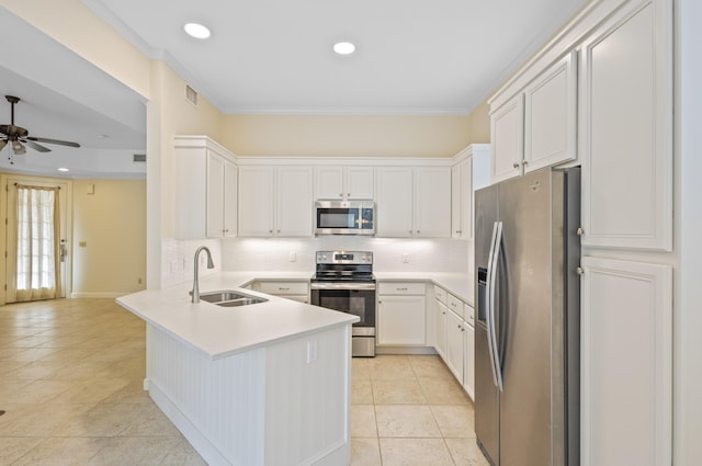 kitchen featuring sink, kitchen peninsula, appliances with stainless steel finishes, ornamental molding, and white cabinets