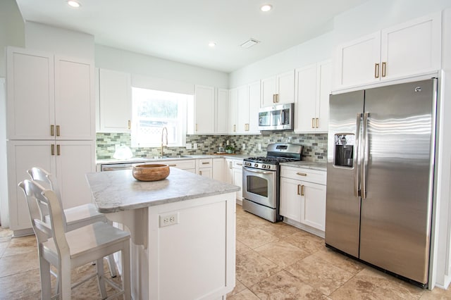 kitchen with tasteful backsplash, a center island, white cabinetry, stainless steel appliances, and a breakfast bar