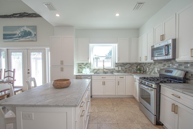 kitchen featuring white cabinets, backsplash, appliances with stainless steel finishes, light stone countertops, and french doors