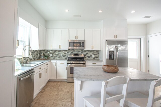 kitchen featuring a wealth of natural light, white cabinetry, appliances with stainless steel finishes, and sink