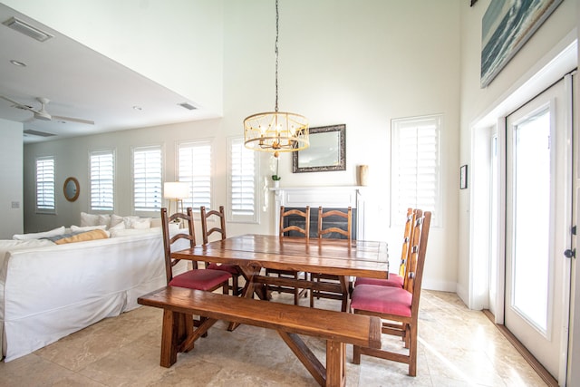 dining area featuring ceiling fan with notable chandelier and a towering ceiling