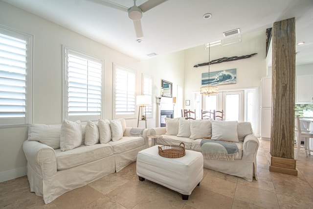 tiled living room featuring ceiling fan with notable chandelier