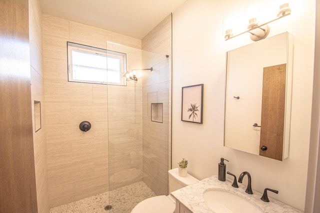 bathroom featuring a tile shower, vanity, and toilet