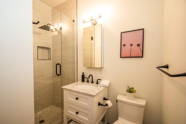 bathroom with a shower with shower door, vanity, and toilet