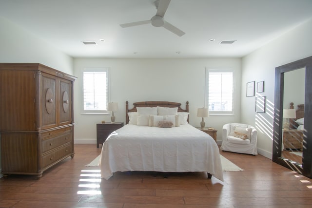 bedroom with multiple windows, dark hardwood / wood-style floors, and ceiling fan