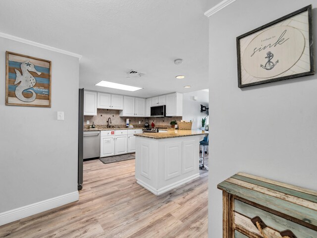 kitchen featuring white cabinets, sink, ornamental molding, stainless steel appliances, and light wood-type flooring