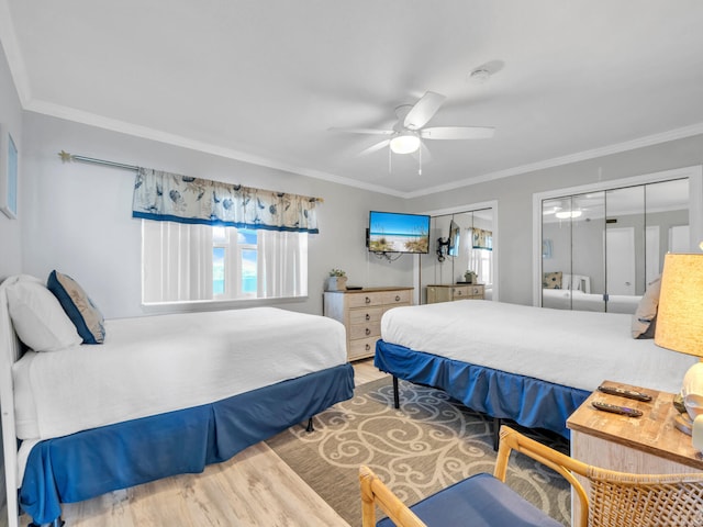 bedroom with ceiling fan, multiple closets, hardwood / wood-style flooring, and ornamental molding