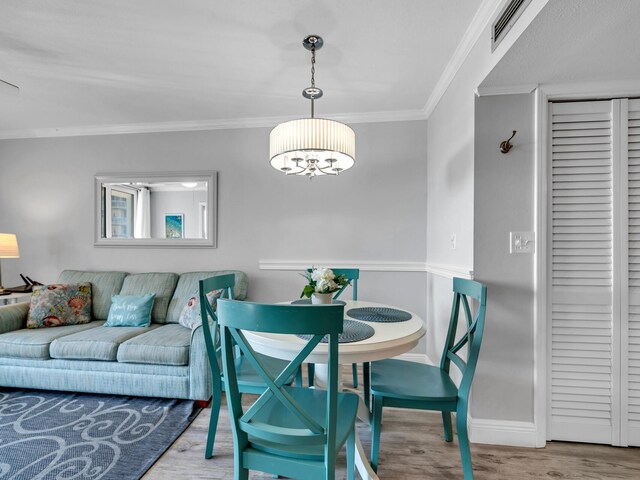 dining area featuring an inviting chandelier, crown molding, and hardwood / wood-style floors