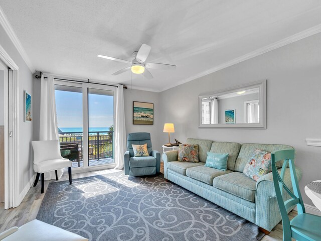 living room with a water view, a textured ceiling, wood-type flooring, crown molding, and ceiling fan